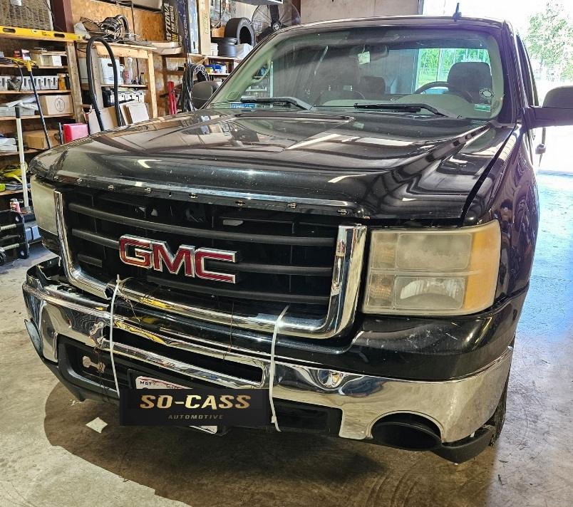 Black GMC pickup in the shop with a So-Cass Automotive plate on the front bumper