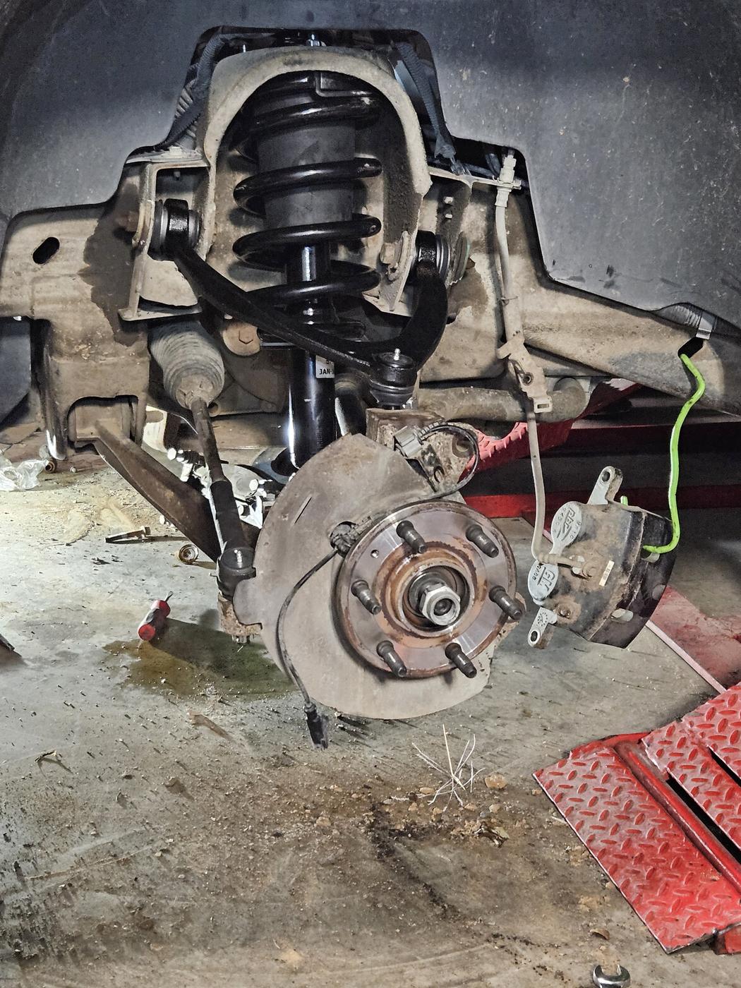 New strut and coil spring installed in a truck wheel well